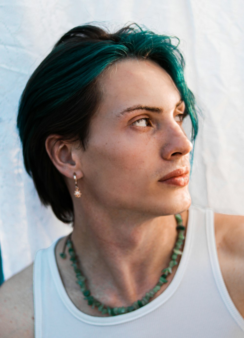 a woman with green hair wearing a white tank top