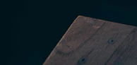 Close-up of a handcrafted oak table with smooth edges contrasting against an onyx black matte finish backdrop.