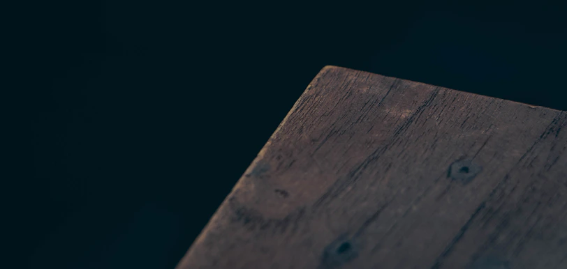 A close-up of rich wood grain on a handcrafted coffee table, contrasting with the black background.