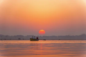 two people in a small boat on the water at sunset