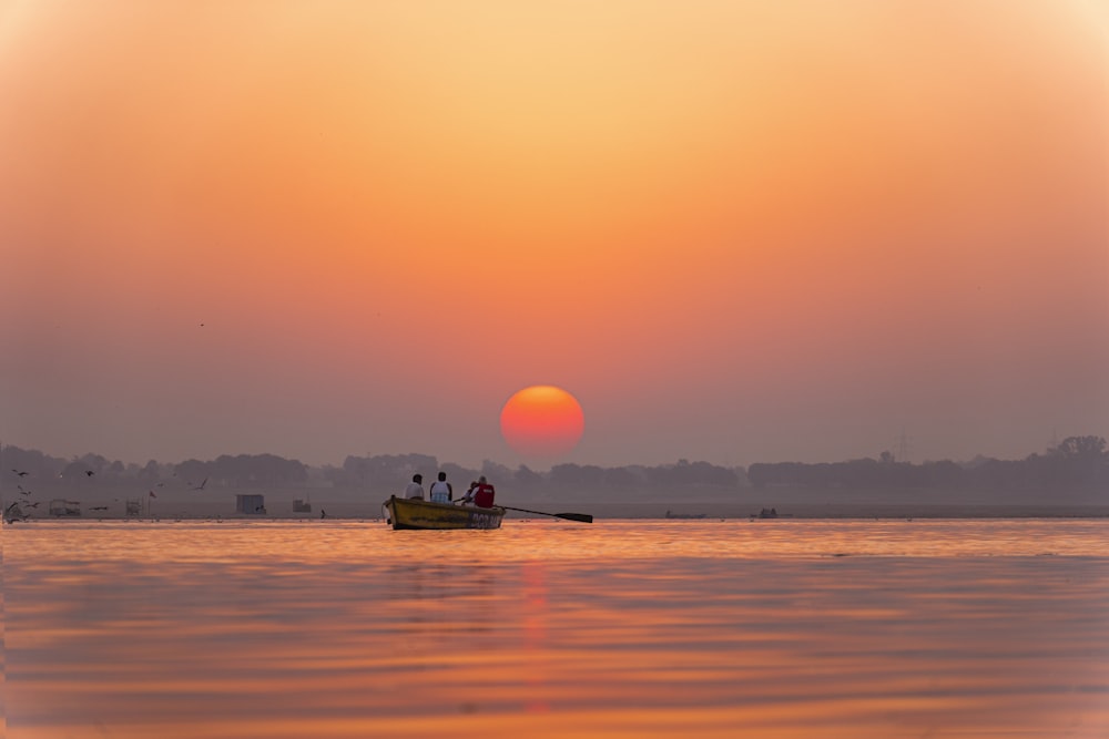 two people in a small boat on the water at sunset
