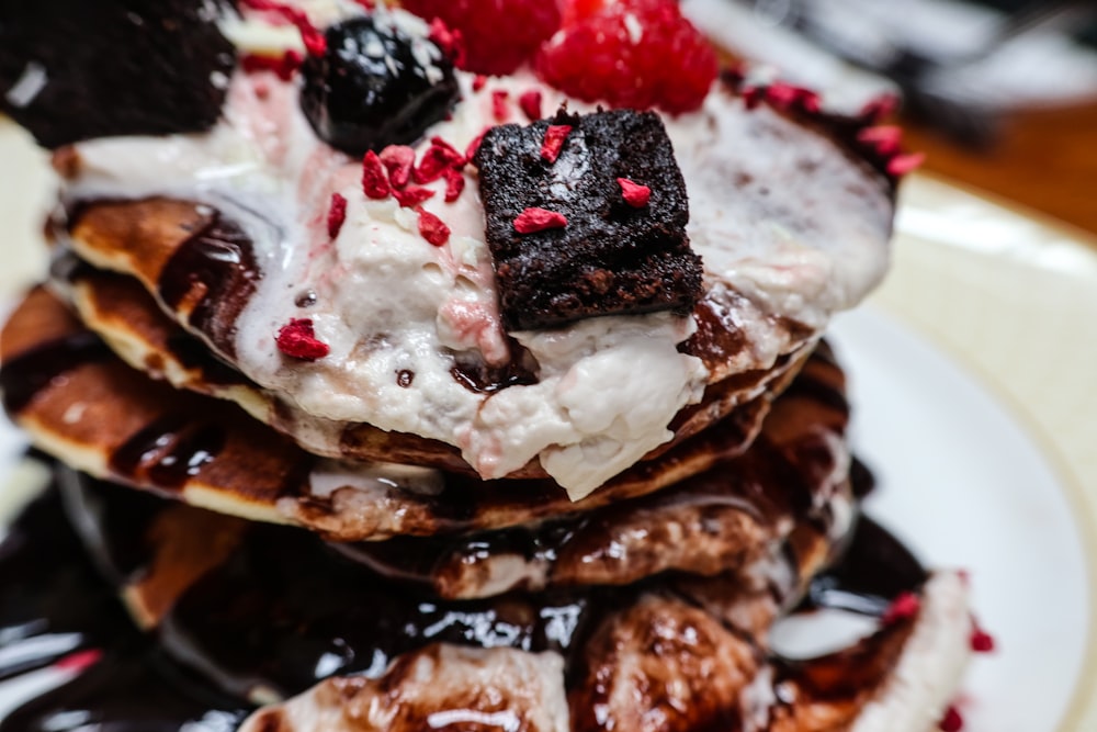 a stack of pancakes covered in whipped cream and berries