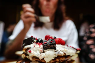 a woman taking a picture of a stack of pancakes