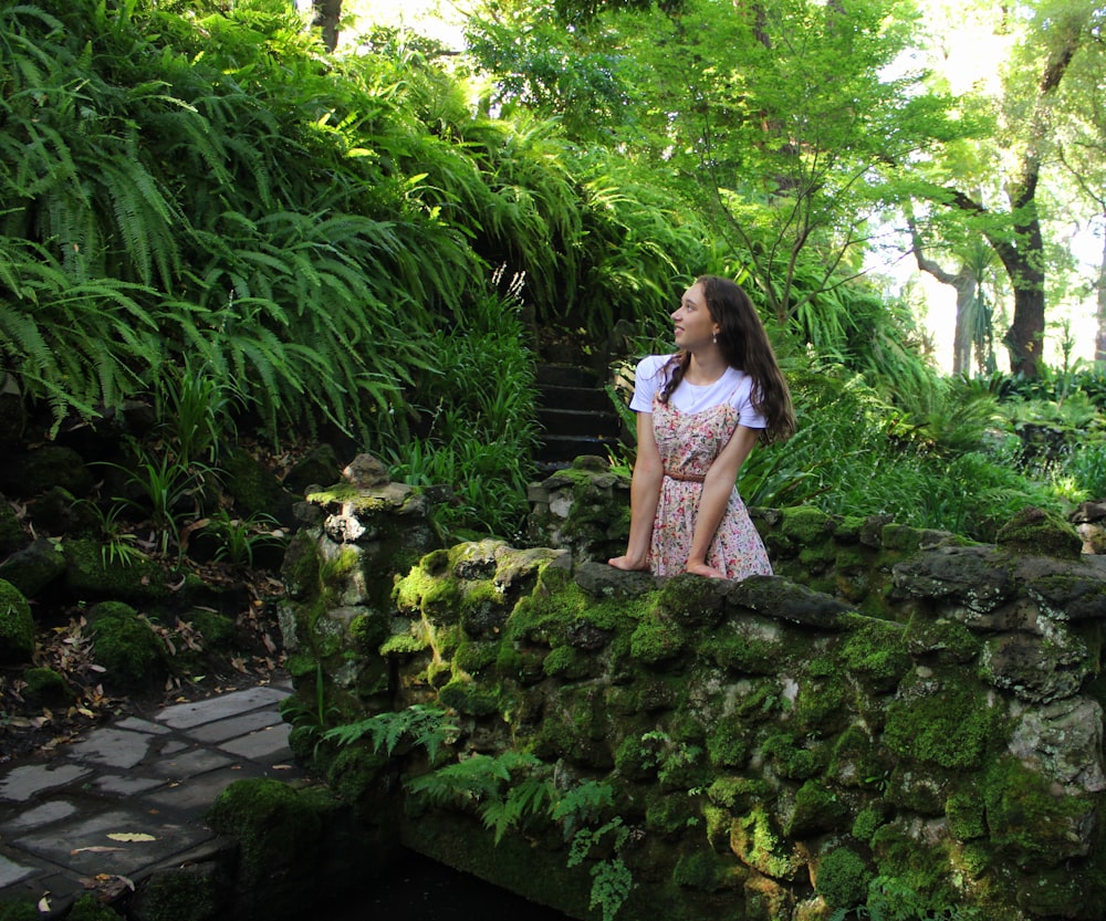 a woman in a dress standing on a stone bridge