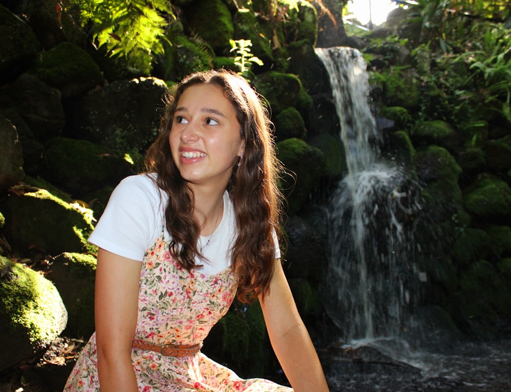 Una niña sentada frente a una cascada