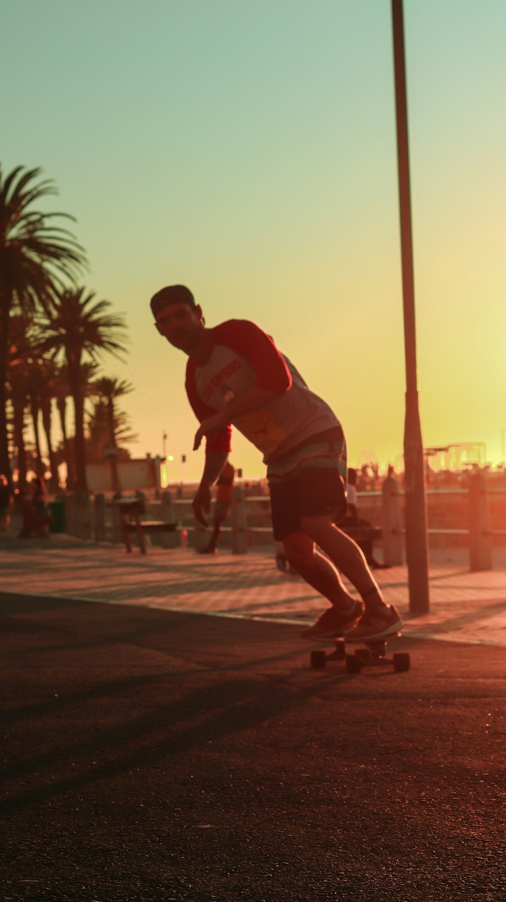 a man riding a skateboard down a street next to palm trees