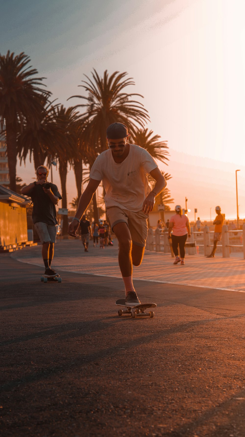 a man riding a skateboard down a street next to palm trees