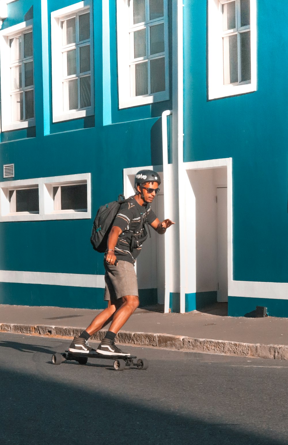 a man riding a skateboard down a street next to a blue building