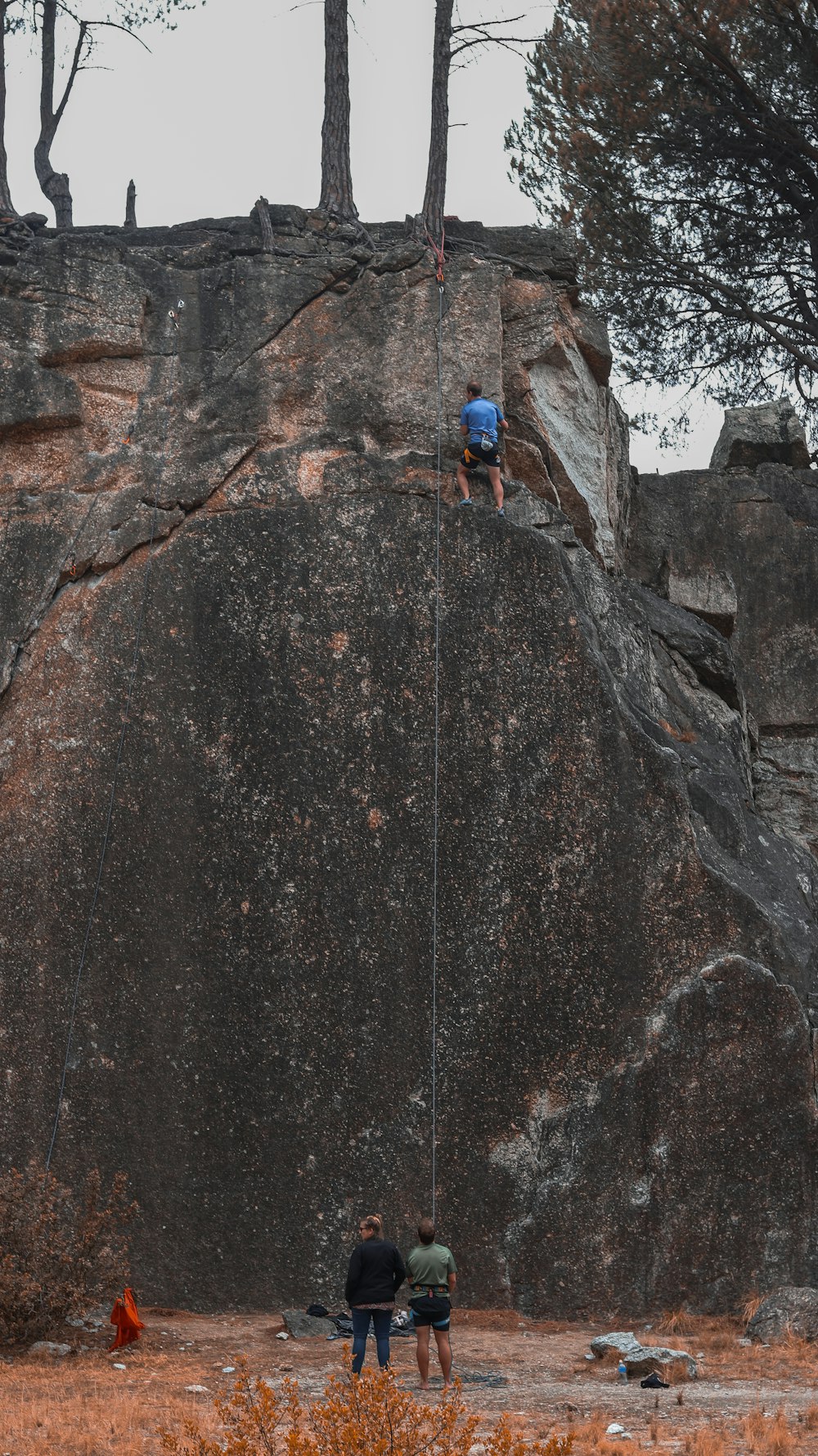 two people are climbing up a large rock
