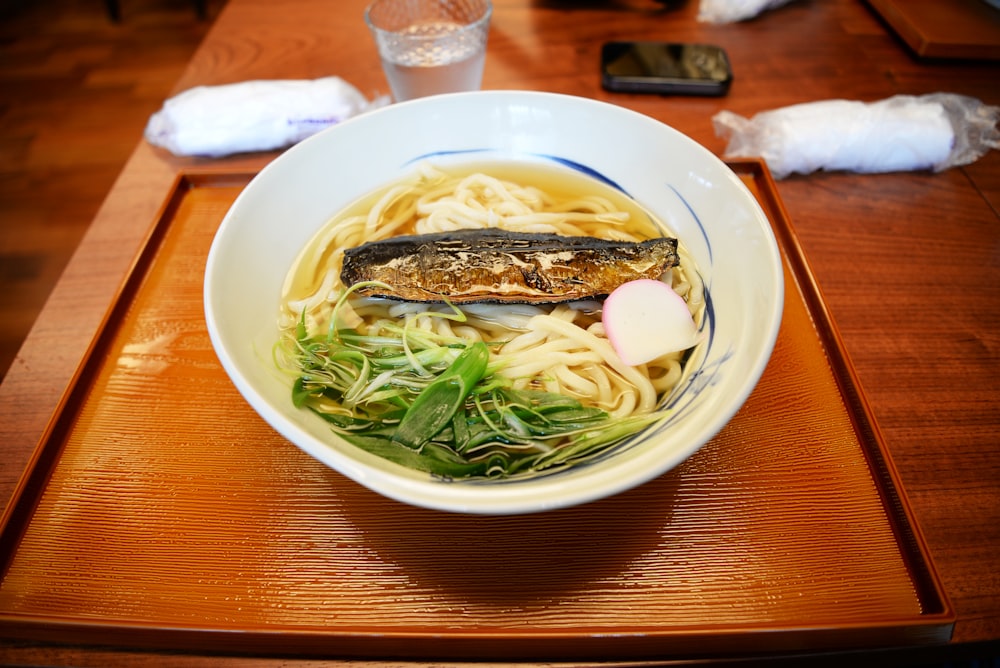 a bowl of noodle soup on a wooden table