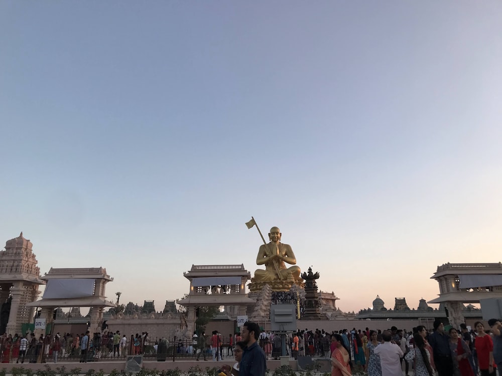 a crowd of people standing around a golden statue