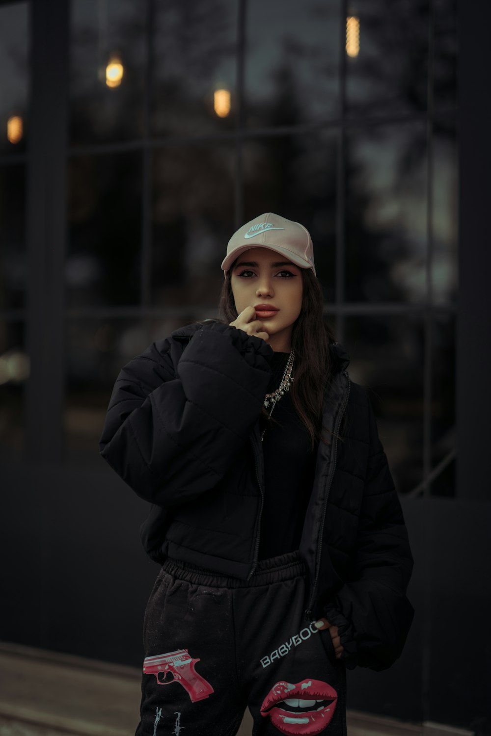 a woman in a black jacket and hat standing in front of a building