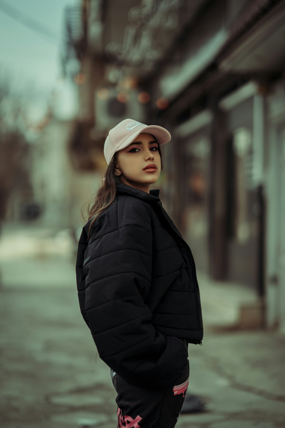 a woman in a white hat is standing on the street