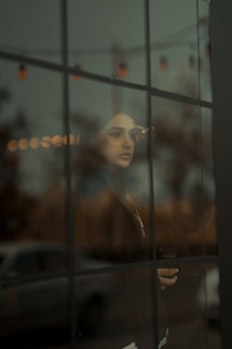 a woman looking out of a window at a car