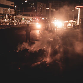 Nighttime city street scene with subtle smoke and glowing streetlights illuminating volunteers.