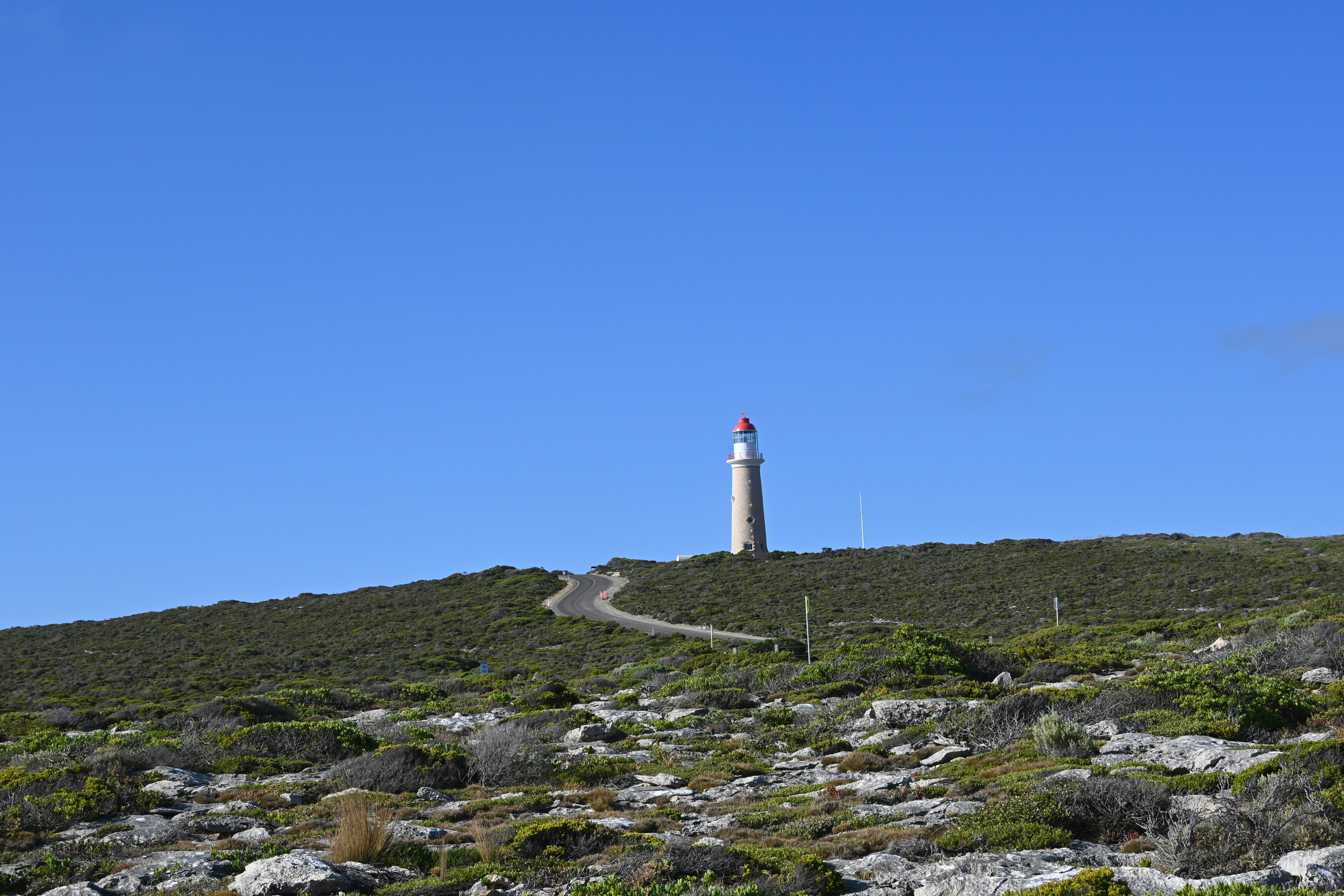 a lighthouse on top of a hill on a sunny day
