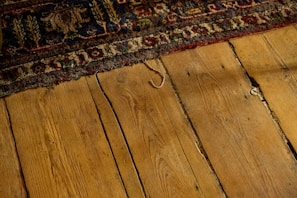 Traditional dhurrie rug with geometric designs laid out on a wooden floor.