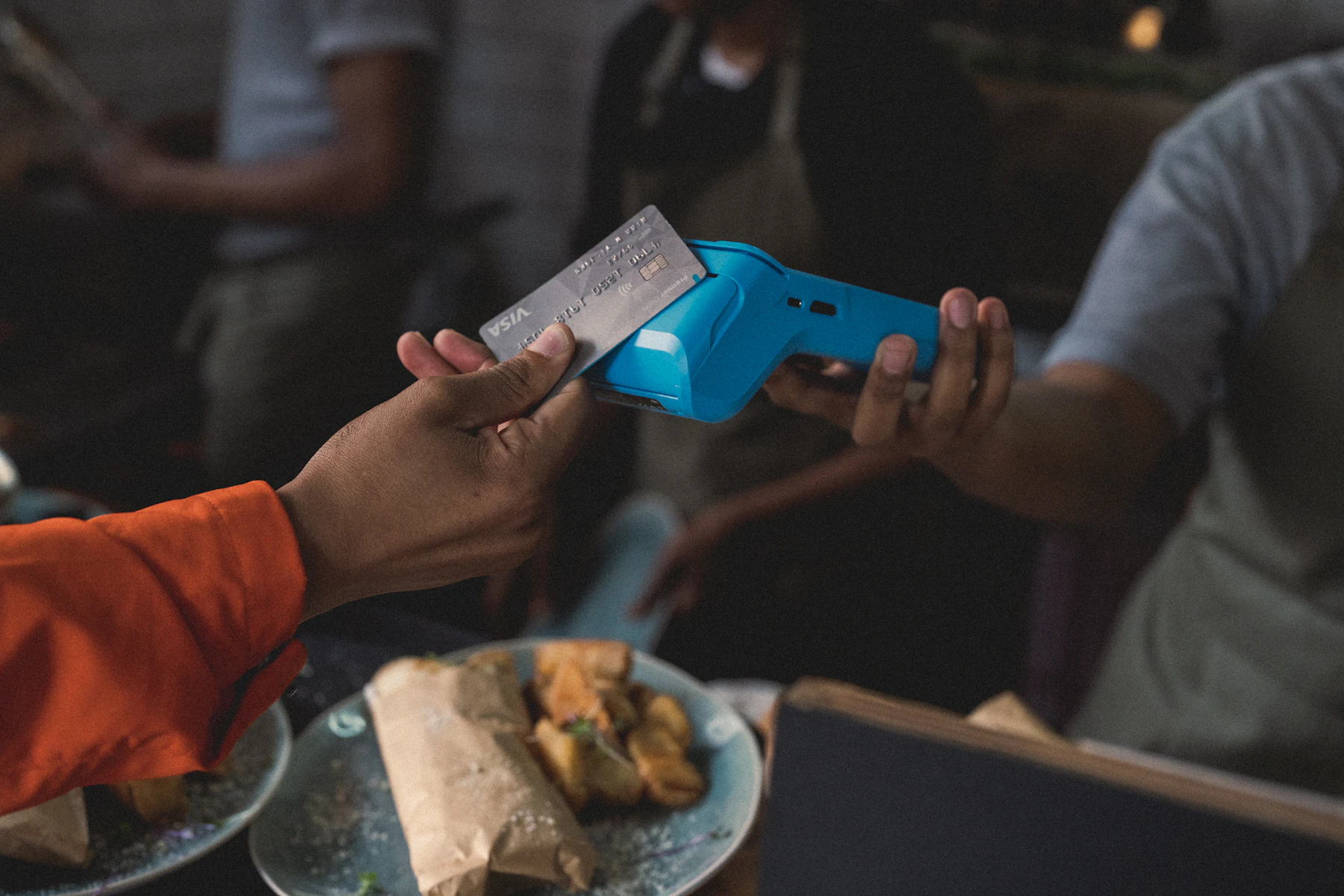 Close-up of a person tapping a card on a payment terminal — the moment when card-machine swap scams happen in Brazilian restaurants and shops. Photo by Yoco Photography