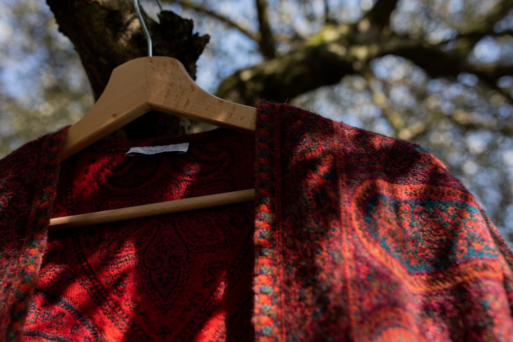 a red jacket hanging on a wooden hanger