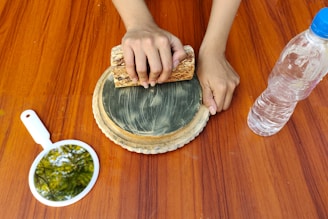 a person using a piece of bread on top of a wooden table