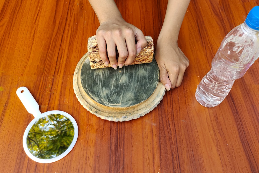 a person using a piece of bread on top of a wooden table