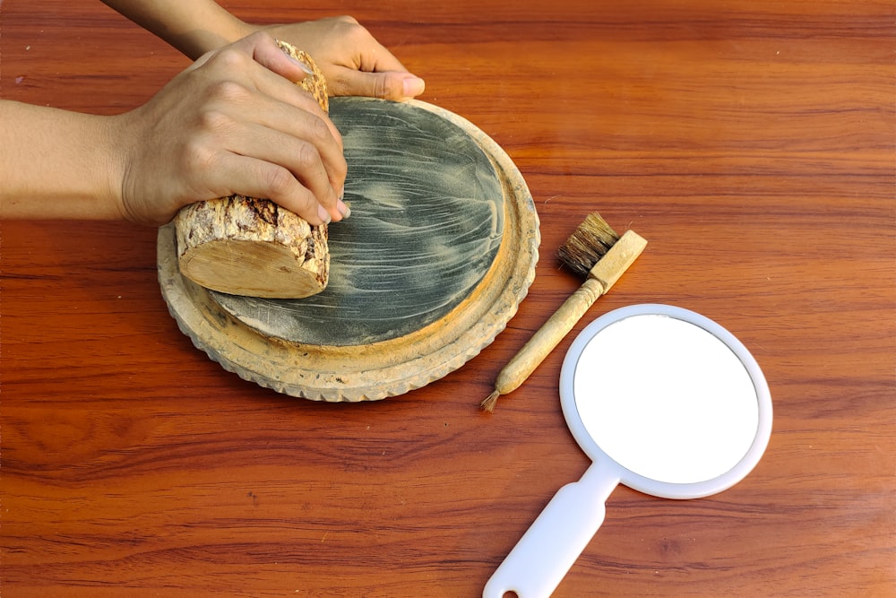 a person's hand holding a brush over a wooden tray