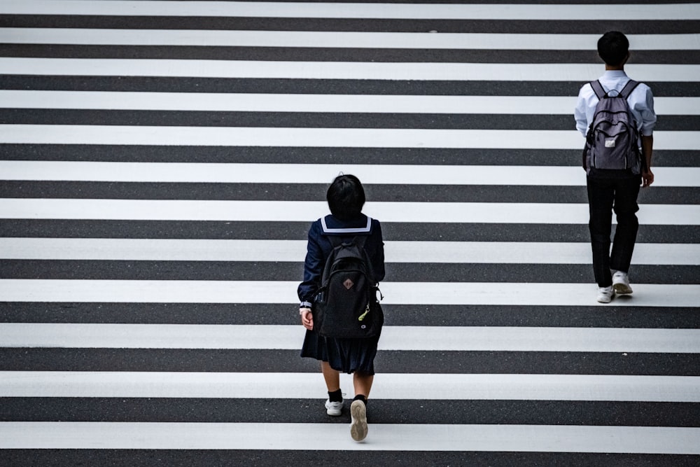 a man and a woman walking across a cross walk