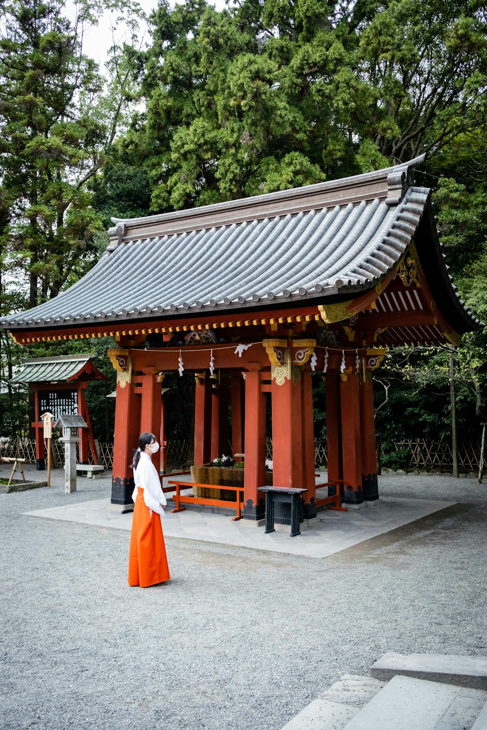a woman in an orange and white dress standing in front of a pagoda