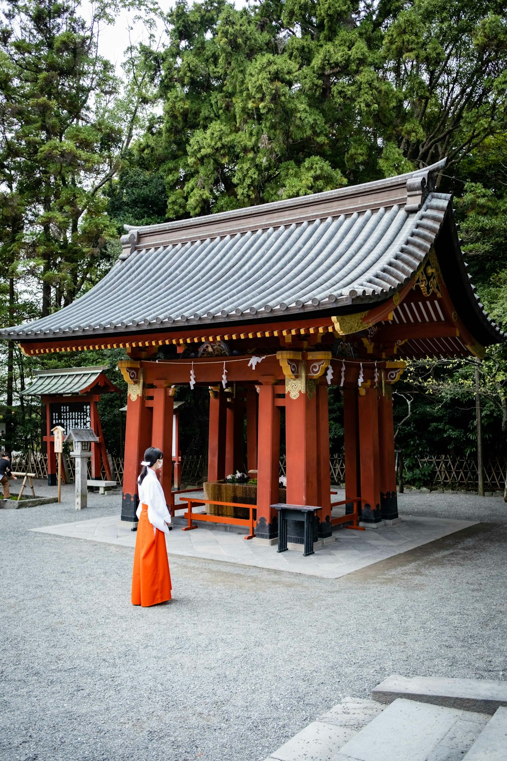 a woman in an orange dress standing in front of a pavilion