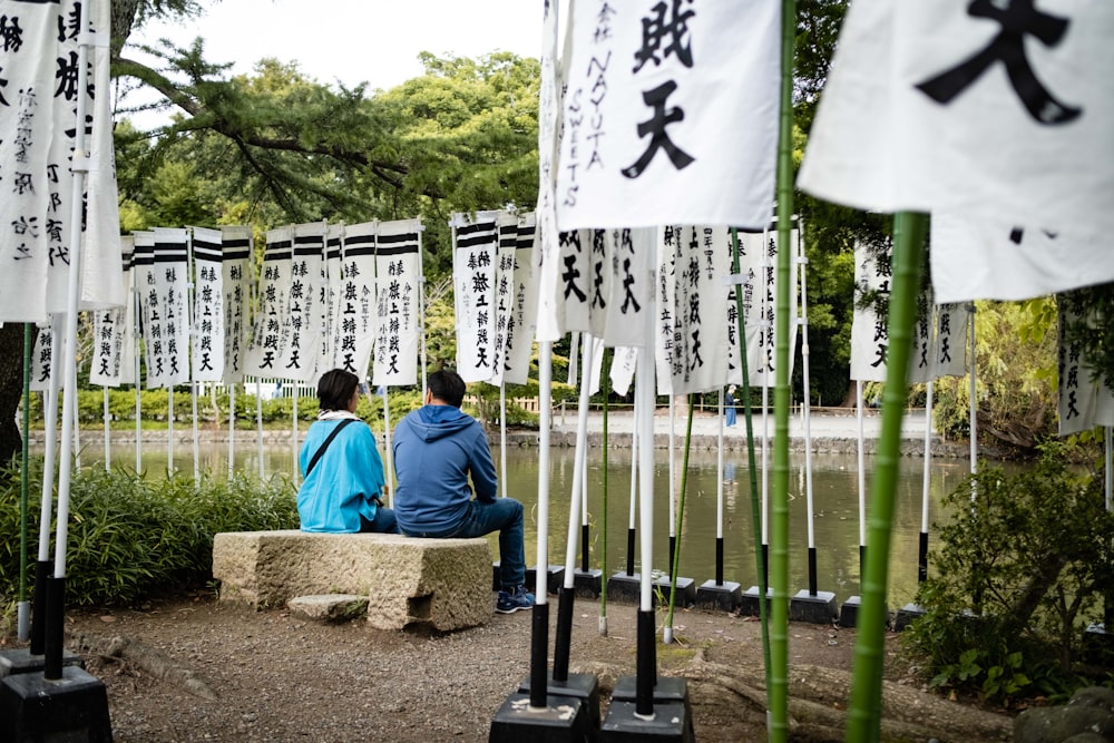 two people sitting on a bench in a park