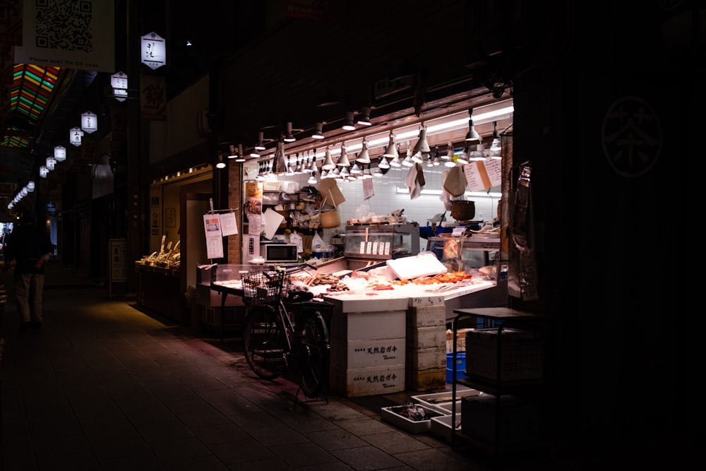 a food stand at night with a bicycle parked in front of it