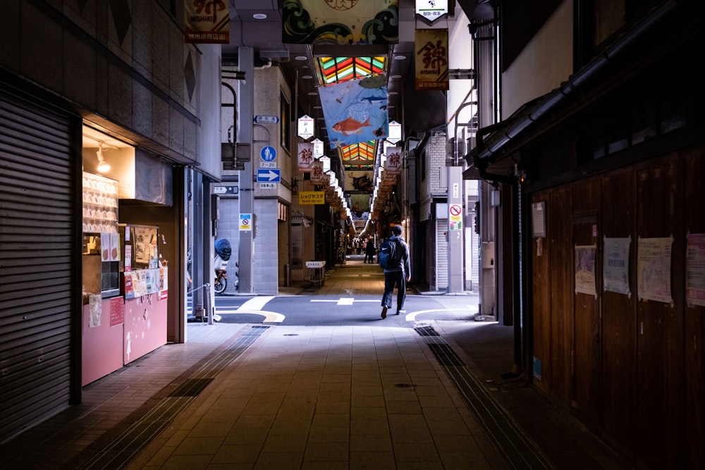a man walking down an alley way at night