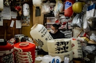 An artisan carefully weaving bamboo strips to create the frame of a lantern in a sunlit workshop.