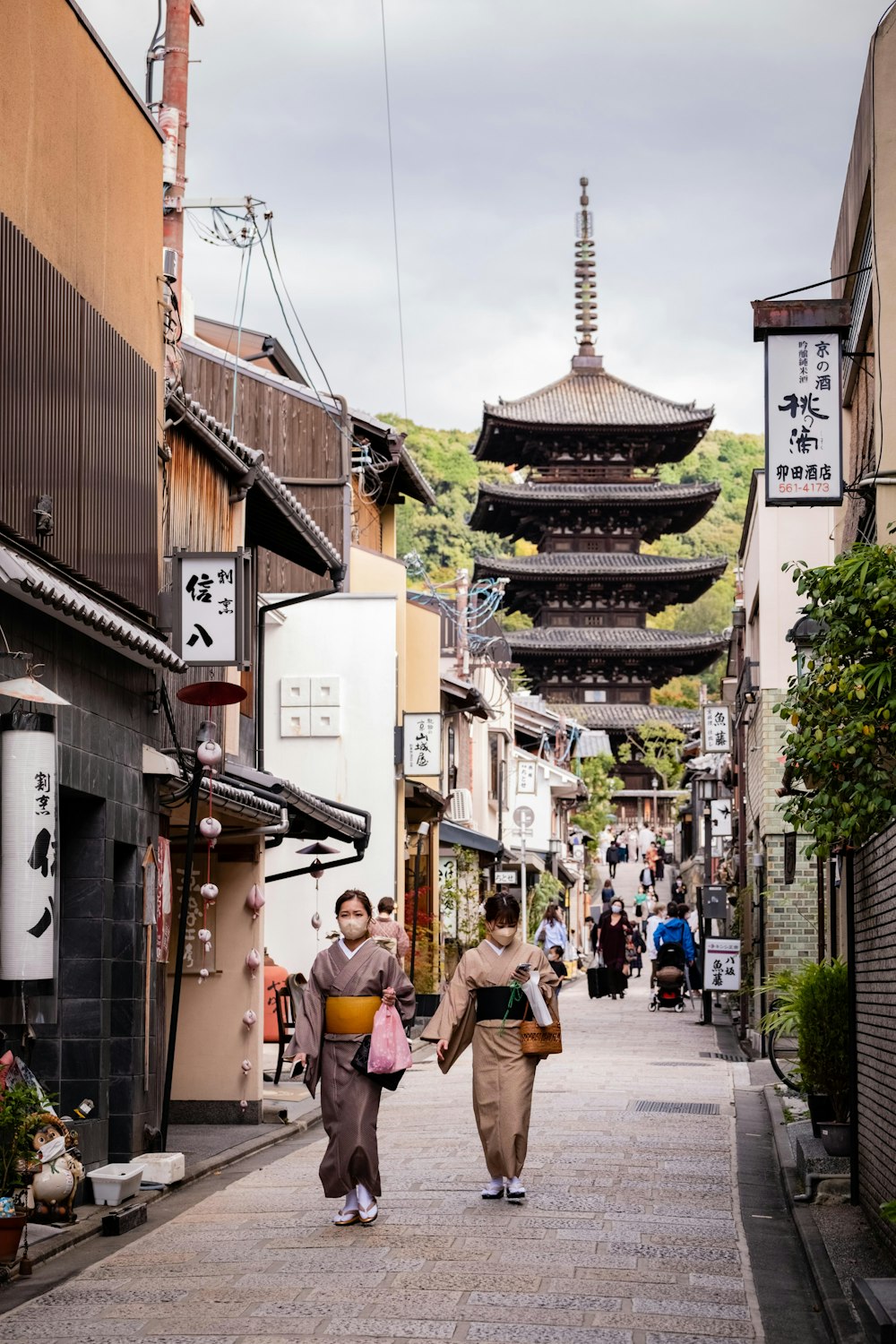 a couple of women walking down a street next to tall buildings