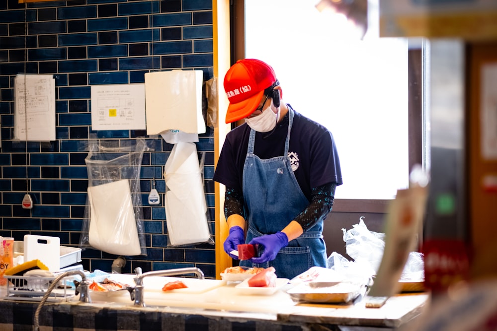 a man wearing a red hat and blue apron