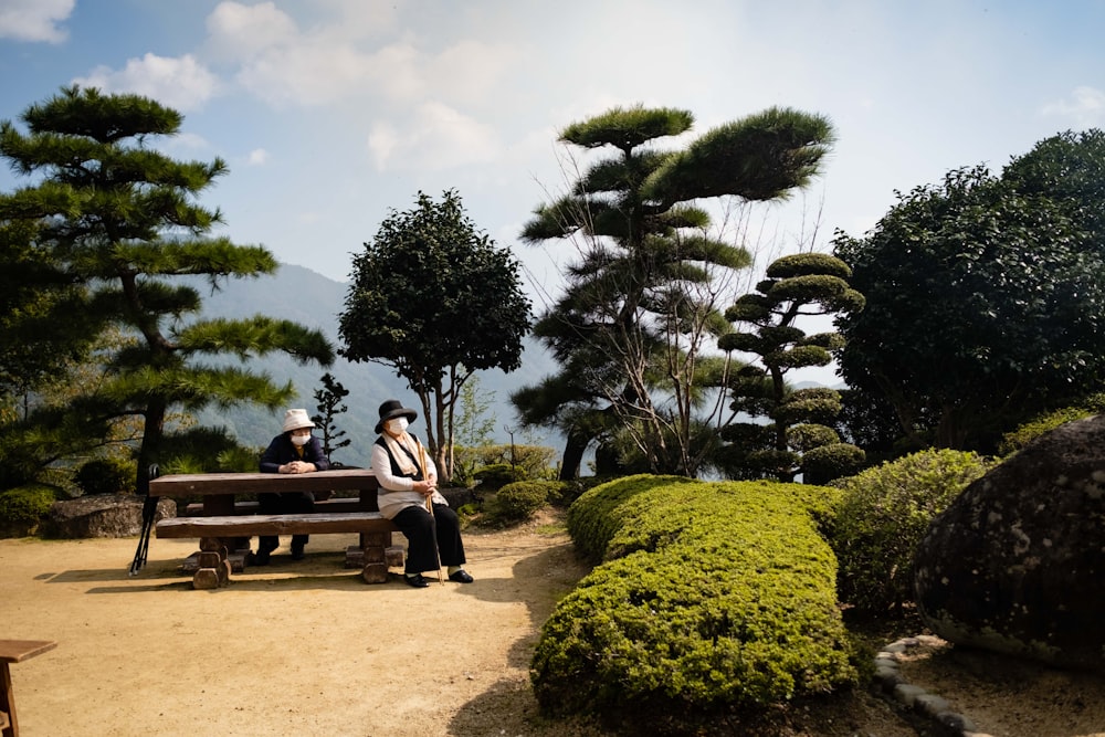 two people sitting on a bench in a park