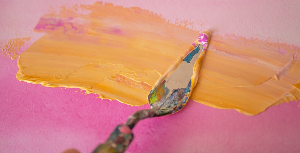 Una persona pintando una pared rosa con pintura amarilla