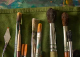 Various paintbrushes and application tools laid out on a wooden table.