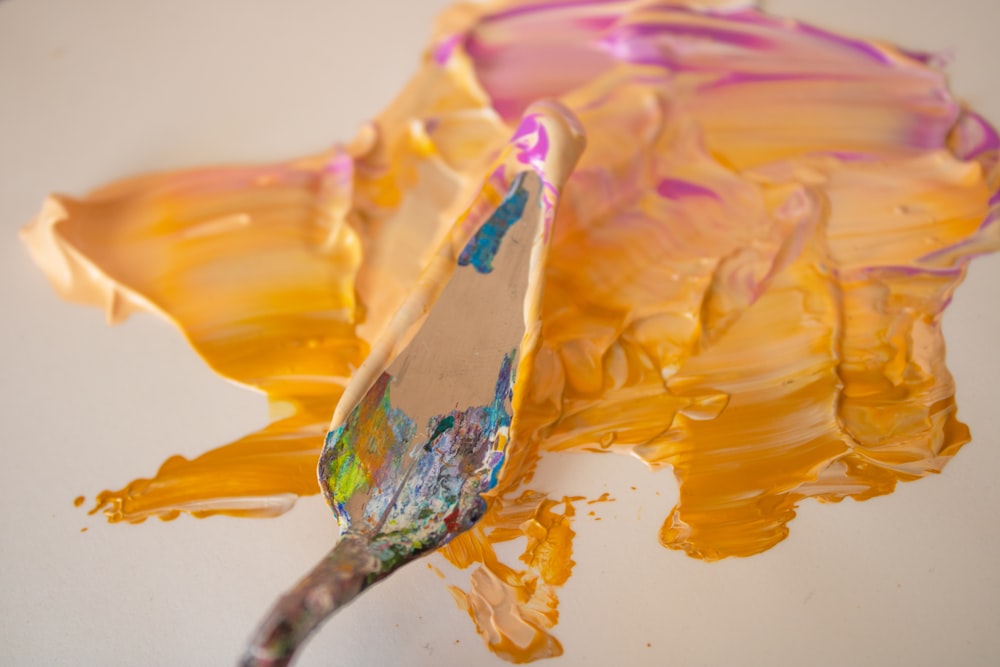 a paintbrush with yellow and purple paint on it