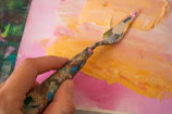 Close-up of hands painting a vibrant globe on textured paper.