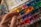 A hand holding a paintbrush hovers over a colorful watercolor palette filled with an array of vibrant hues. The palette is splattered with various colors, indicating frequent use. The scene captures the tools of an artist in mid-creation.