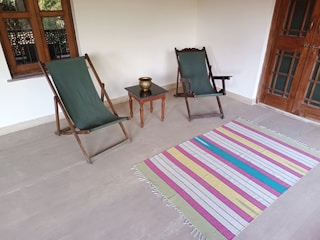 A colorful outdoor rug laid out on a wooden porch, adding warmth and style.