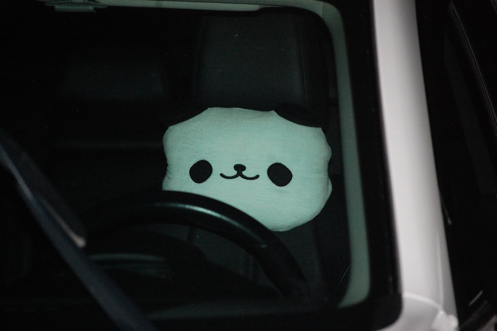 a stuffed animal sitting in the drivers seat of a car