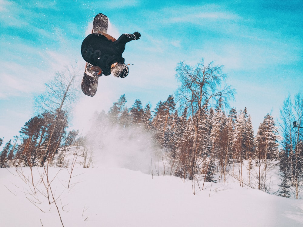 a man flying through the air while riding a snowboard