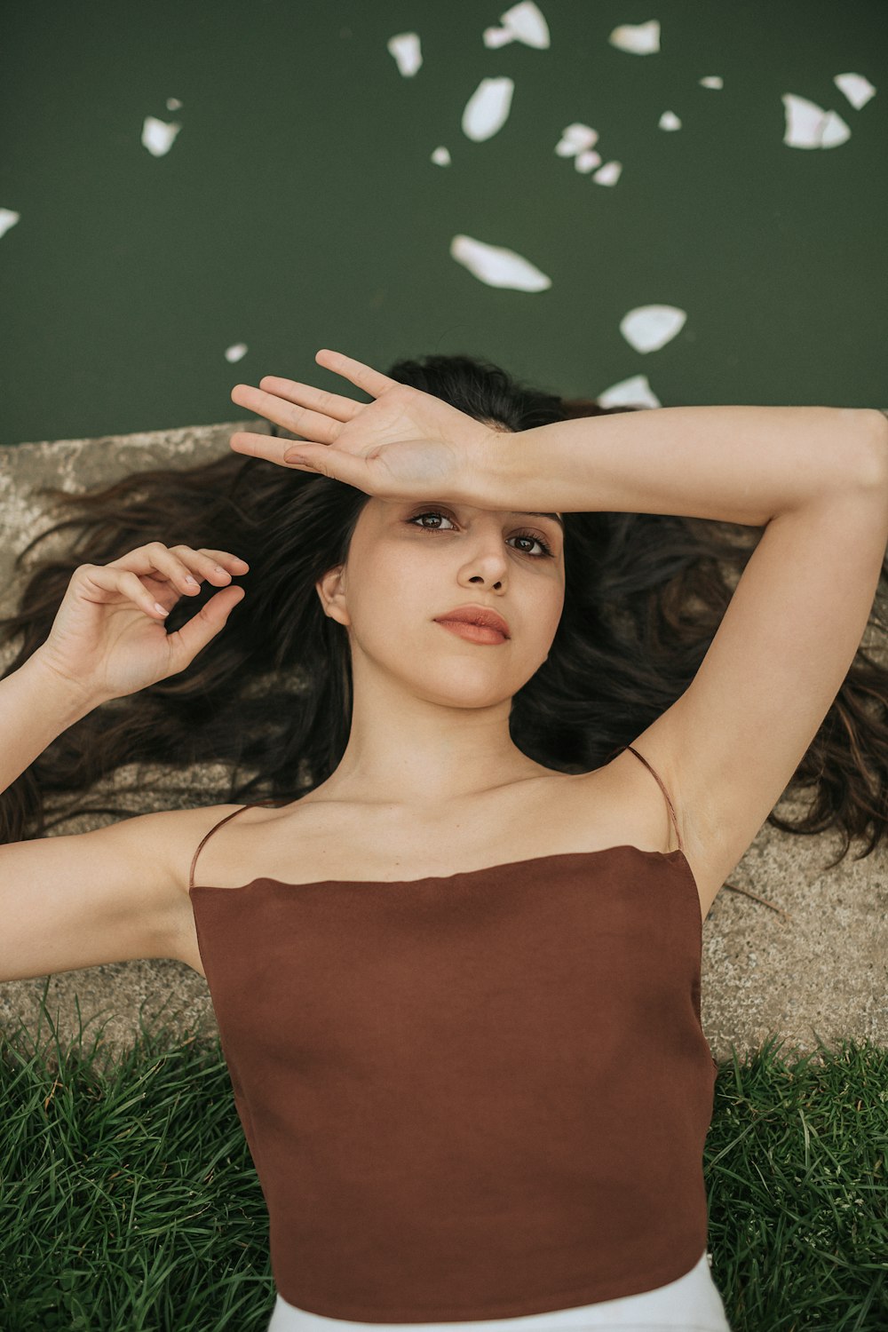 a woman laying in the grass with her hands on her head