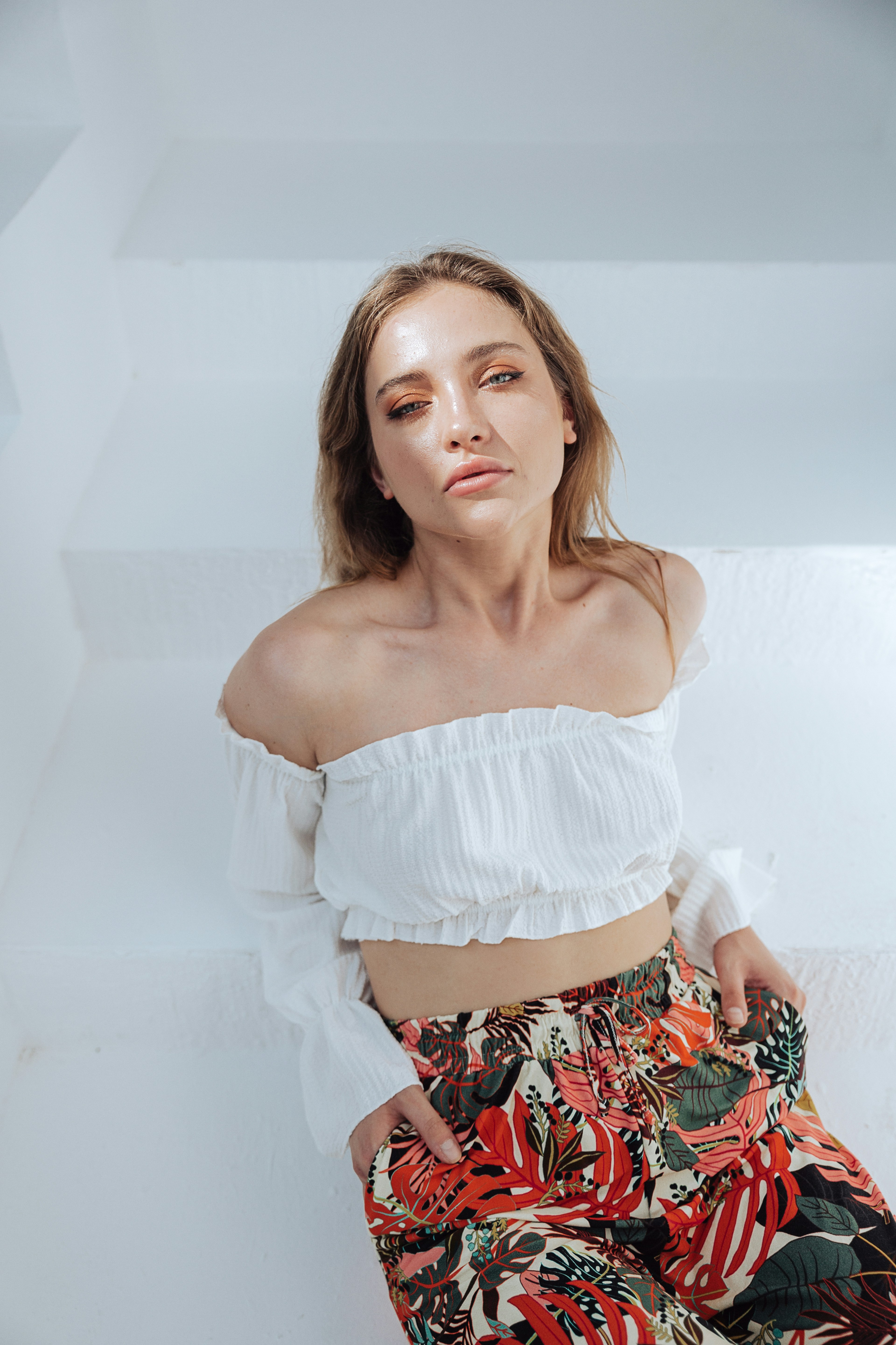 a woman wearing a white top and floral pants