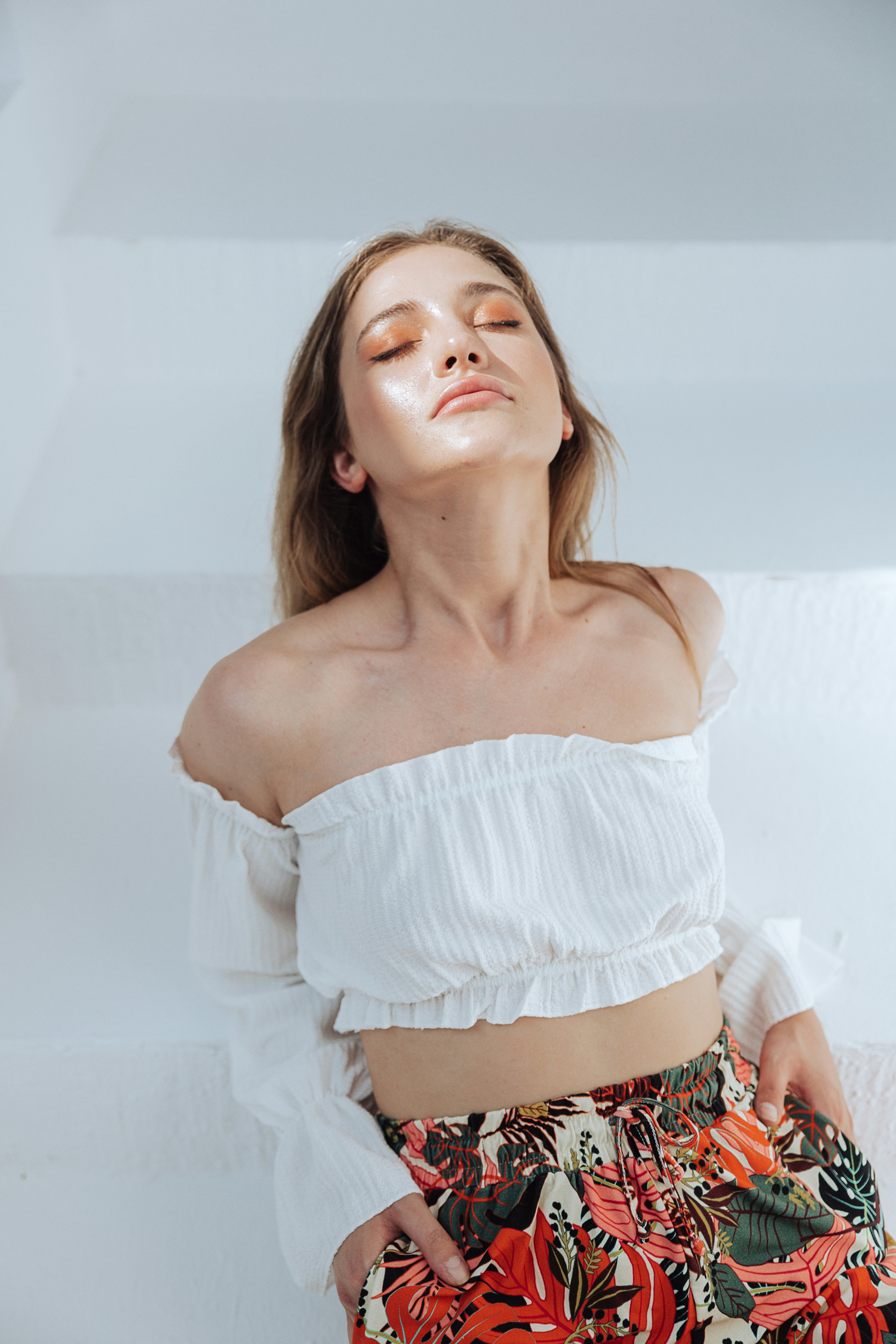a woman wearing a white top and floral skirt