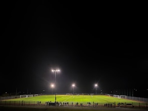 Players competing fiercely under glowing LED floodlights on the turf.