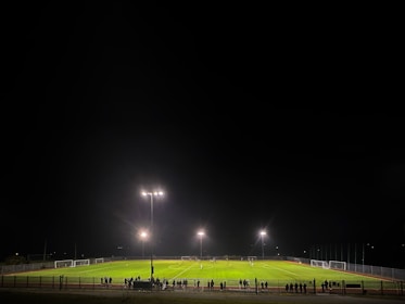Players competing fiercely under glowing LED floodlights on the turf.