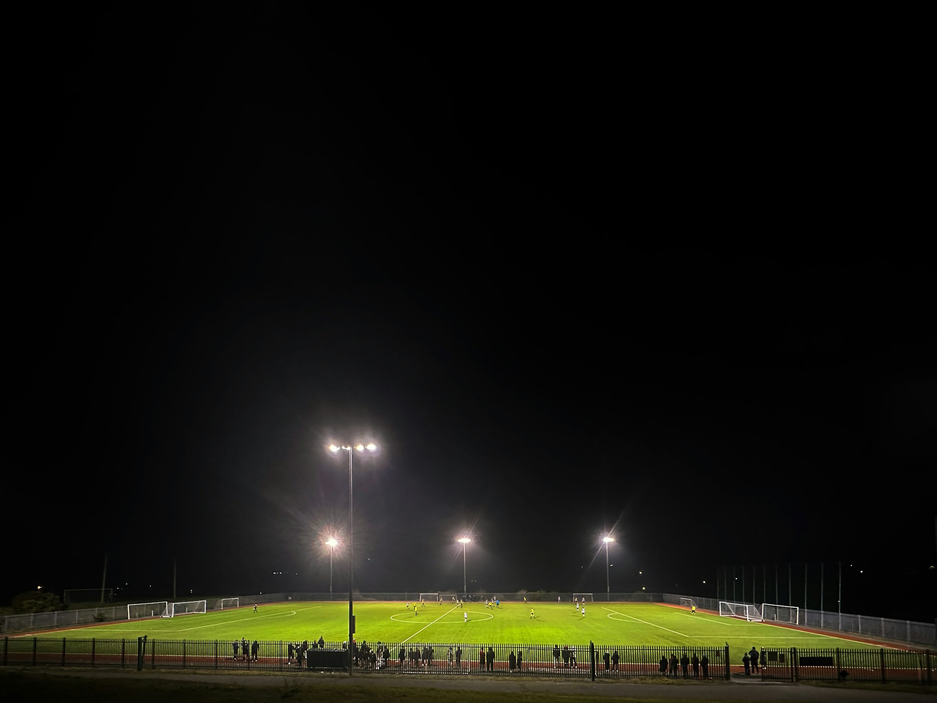 Close-up of a player skillfully dribbling the ball on the lush green pitch under bright stadium lights.